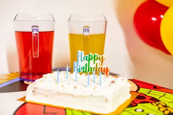 A birthday cake with jugs of juice at a Happy Town party