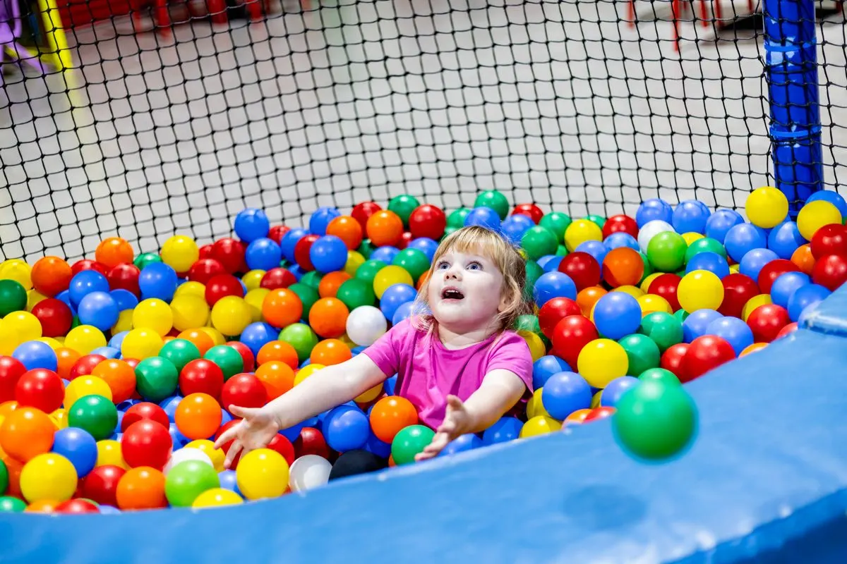 A delighted little girl in the ball pit