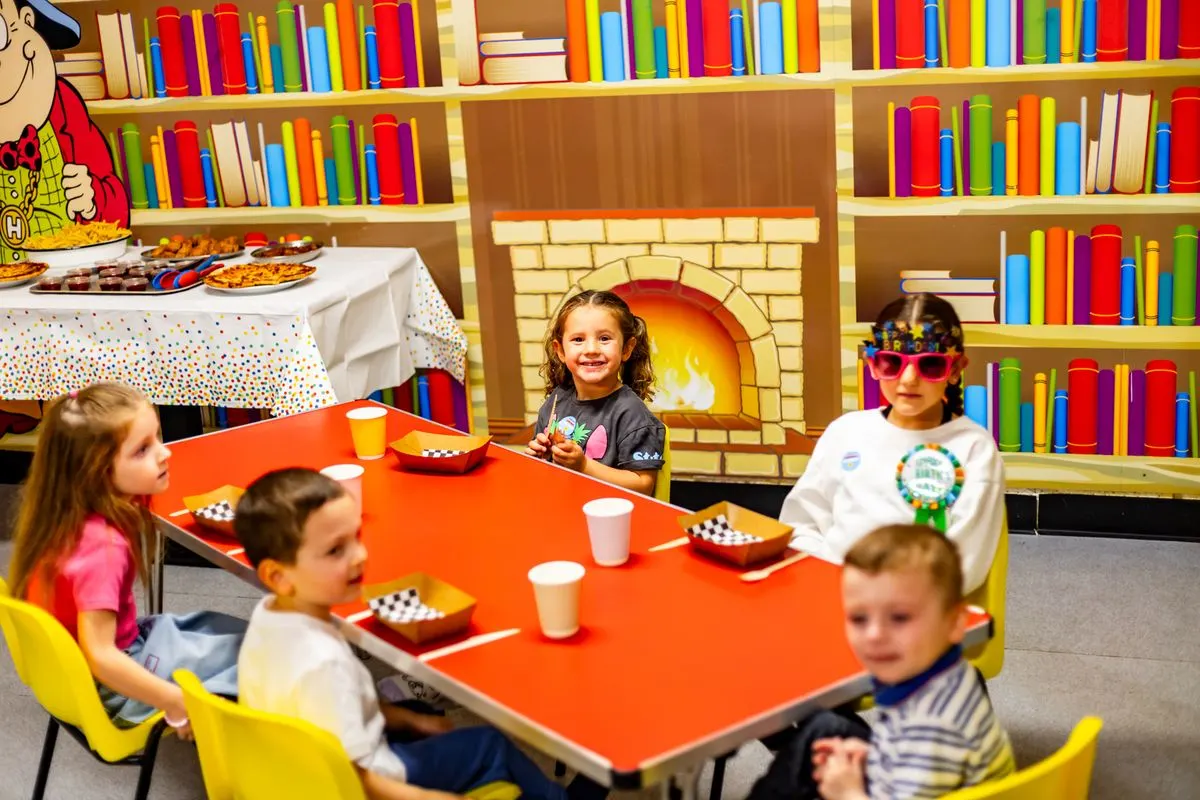 Children at a party table in a Happy Town party room